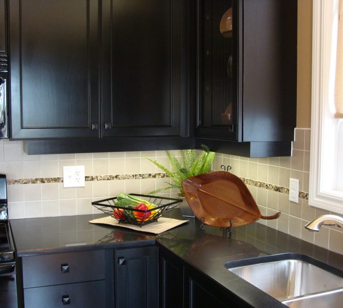 Modern kitchen design in dark color for visual impact, black granite countertops, undermount sink